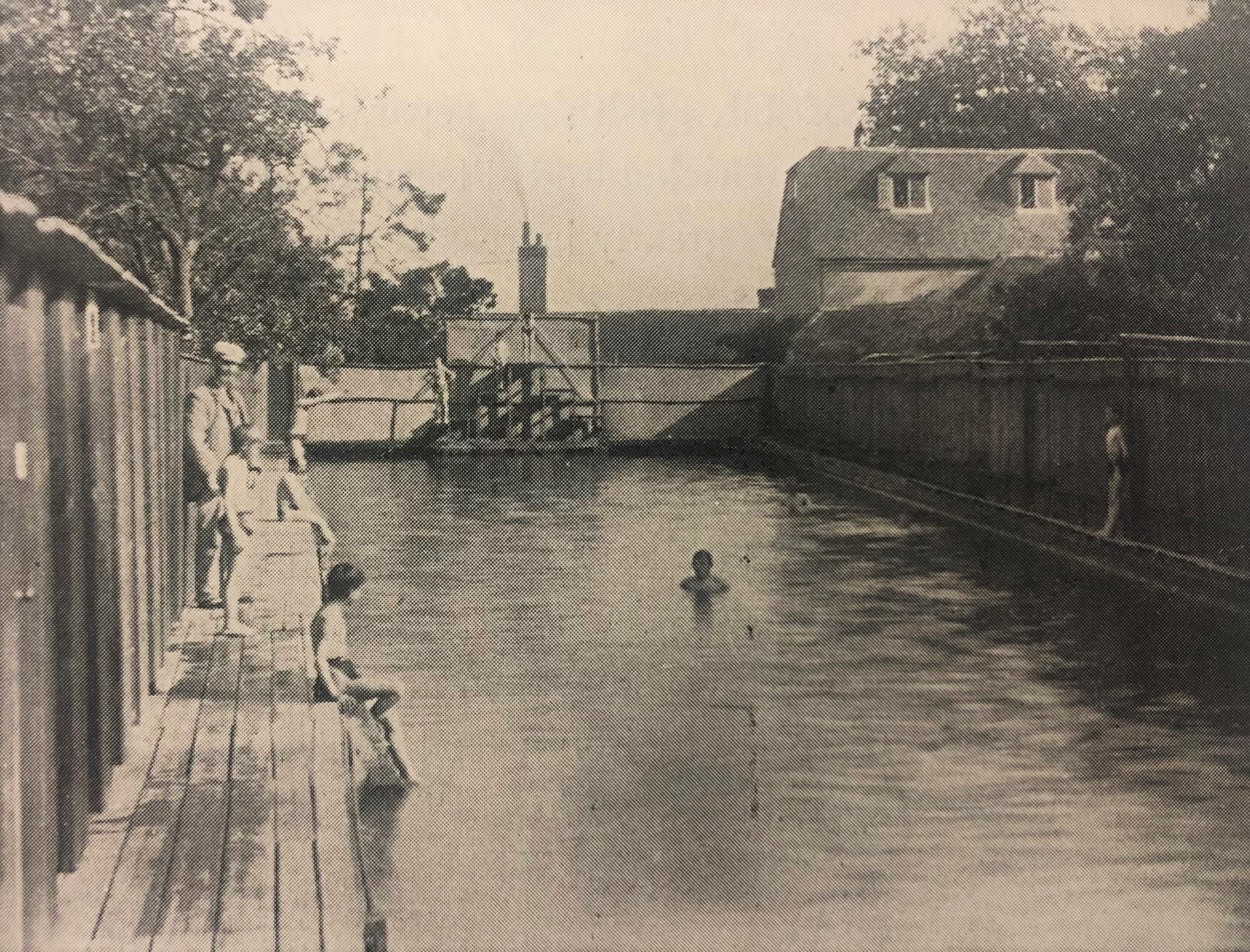 Black and white photo of people swimming outdoors