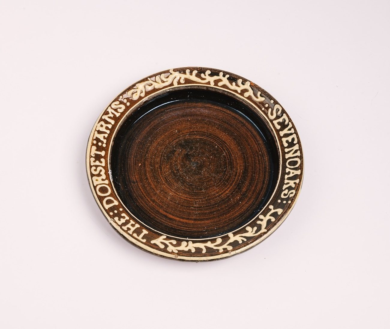 Brown slip-ware pottery dish with cream decoration and inscription