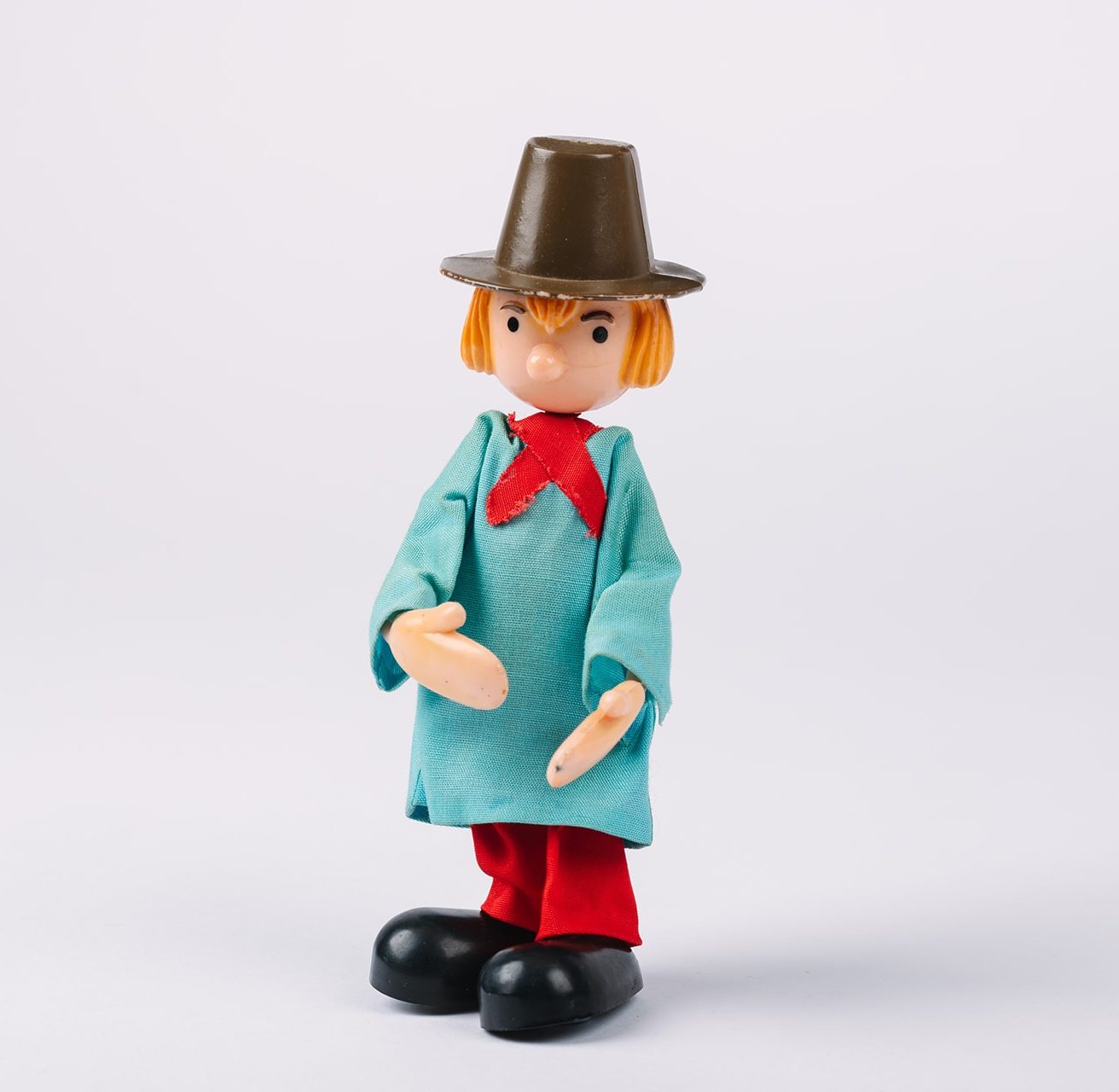 Plastic figurine in brown hat, blue textile smock and red trousers